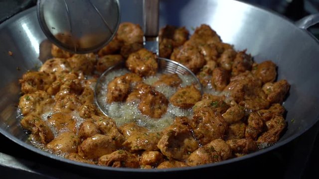 Fried fish cake in a frying pan full of hot oil. Popular Thai street food.