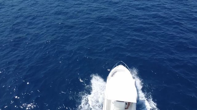 White Speed Boat Travelling And Cruising At The Gulf Of Castellammare During Summer Near The Scopello Province Of Trapani In Sicily, Italy. - aerial drone flying behind