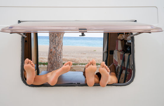 Window of a camper van. In the window there are four legs