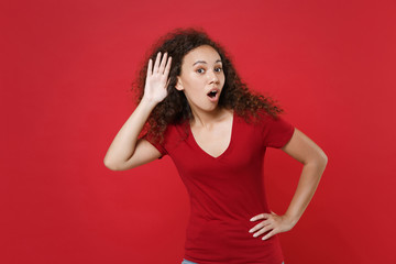 Shocked young african american woman girl in casual t-shirt posing isolated on red background...