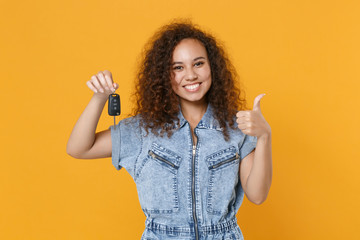 Smiling young african american girl in casual denim clothes isolated on yellow wall background...