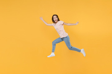 Fototapeta na wymiar Full length side view portrait of cheerful funny young woman 20s wearing pastel pink casual t-shirt posing jumping spreading hands and legs looking camera isolated on yellow color background studio.