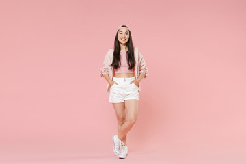 Fototapeta na wymiar Full length portrait of smiling young asian girl in casual clothes, cap isolated on pastel pink wall background studio portrait. People lifestyle concept. Mock up copy space. Holding hands in pockets.