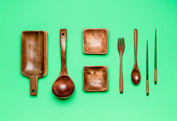 Eco-friendly kitchenware isolated on a green background. Wooden kitchen utensils flat lay.