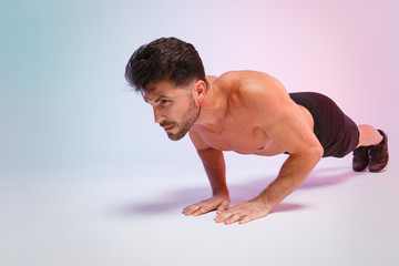 Obraz premium Full length portrait young fitness sporty strong guy bare-chested muscular sportsman isolated on white background studio portrait. Workout sport motivation lifestyle concept. Doing push-ups exercises.
