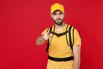 Sad delivery employee man guy 20s in yellow cap t-shirt uniform thermal bag backpack with food work as courier isolated on red background studio. Service during quarantine coronavirus covid-19 virus.