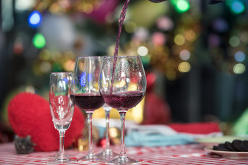 Pouring red wine into glass on Christmas tree background, Christmas celebration concept.