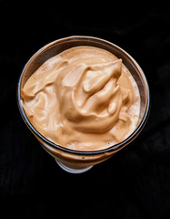 Dalgona Coffee in close-up isolated on dark background.