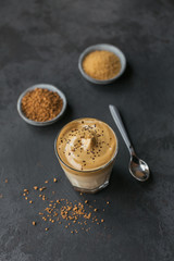 Glass of Iced Dalgona Coffee, trendy fluffy creamy whipped coffee and milk on black background.