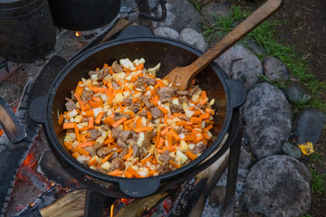 Pilaf is cooked in a large cauldron. Cooking on a fire, in the open air.