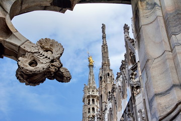 Statue on spire of Milan Cathedral on blue sky background, Milan, Italy. 