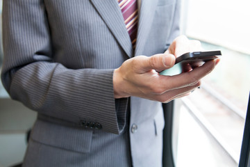 電車でスマホを見るビジネスマン