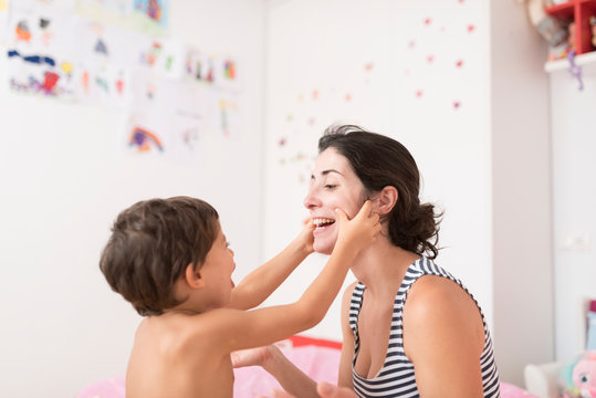 Little boy plays with his mother in the bedroom
