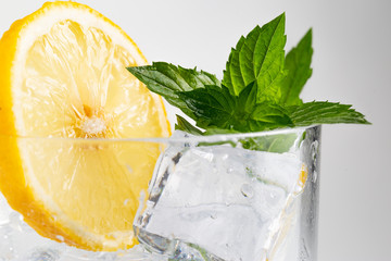 Glass of mojito decorated with a sprig of mint and slice of lemon on white background