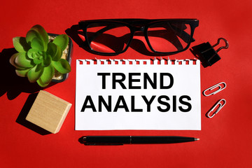 trend analysis. text on white paper over red background. near plants, paper clips, pens