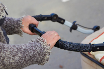 female hand on a stroller,mother holds the handle of a stroller and walks with the baby