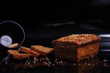 Homemade black bread on a black background. Photo in section.