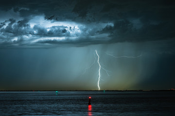 Dramatic image of a lightning bolt striking down from a high based thunderstorm
