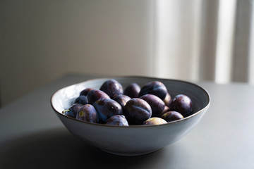 fresh plum fruits in grey bowl on table