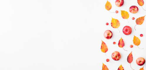 Flat lay pattern with colorful autumn leaves and small red apples on a white background