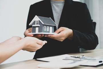 Hand a real estate agent, hold the home model, and explain the business contract, rent, buy, mortgage, loan, or home insurance to the buyer woman