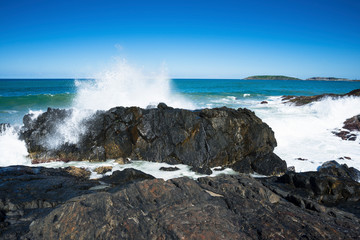 A wave crashes against the rocks at Macauleys Headland in Coffs Harbour, Australia. 