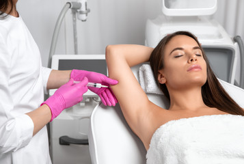 Aesthetic cosmetologist makes lipolytic injections to burn fat on the arm and body of a woman. Female aesthetic cosmetology in a beauty salon.Cosmetology concept.