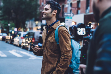 Happy man walking with smartphone in hand at street