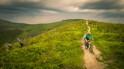 Cycling woman riding on bike in autumn mountains forest landscape. Woman cycling MTB flow trail track. Outdoor sport activity.