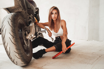 Obraz na płótnie Canvas Garage indoors and cute girl with custom motorbike