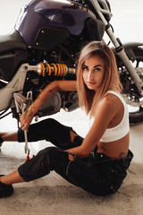 Fototapeta na wymiar A modern sport motobike with cute blond girl with some tools on her hands