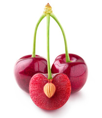 Isolated cherries. Three sweet cherry fruits on one stem, one cut in half with a pit, isolated on white background