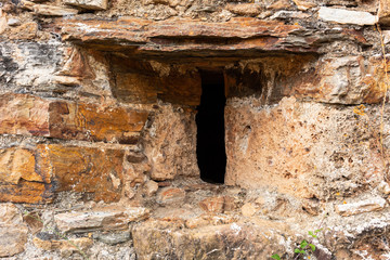 Aspillera or window in a medieval castle, with enchanted dark background and stone wall