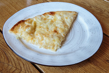 Large piece of pizza with cheese. Hot tortilla with cheese, Khachapuri, Caucasian kitchen.