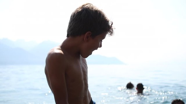 Child entering lake cold water. Young boy refreshing body
