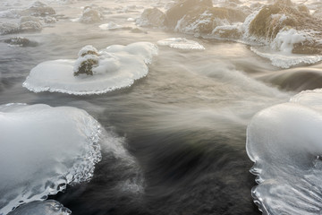 Sheets of ice floes in flowing river Isar near Munich on cold foggy winter day