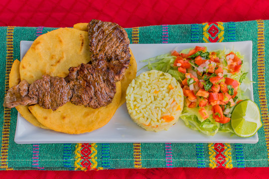 typical Salvadoran dish, roast beef, rice, chirmol and pupusas