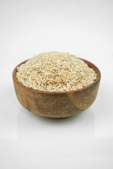 brown rice in a wooden bowl isolated on white, vertical studio shot