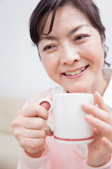 マグカップで飲み物を飲むミドル女性