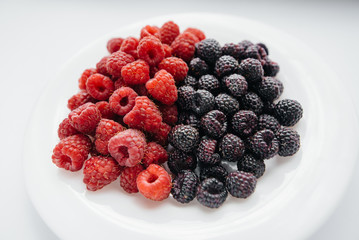 Black and red raspberry close-up on a white background. Healthy food, natural vitamins. Fresh berries