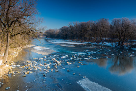 Shallow spot of the river Isar in Munich with ice on rocks on a cold sunny winter day