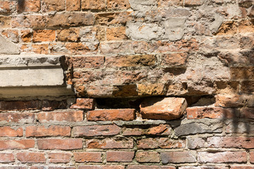 Dilapidated with potholes old brick wall of the building, made of red brick, close up. Background or texture.
