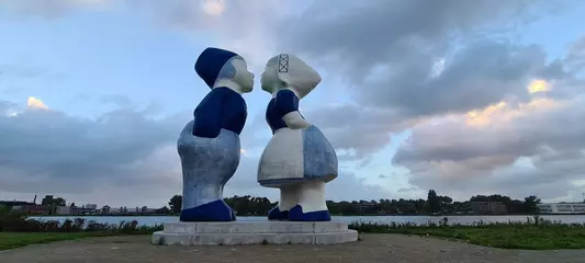 Deurstickers Large kissing Dutch man and woman in  Delfts blue with traditional costumes. © Sorbotrol