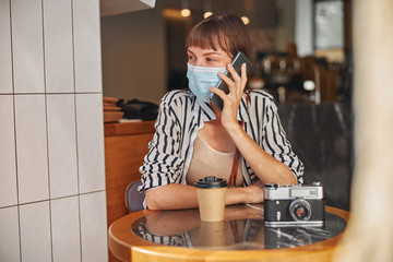 Female in mask is talking on smartphone