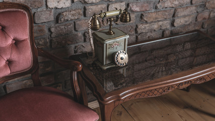 Elegant vintage old telephone on elegant wooden table against brick wall relaxing antique interior vintage decoration