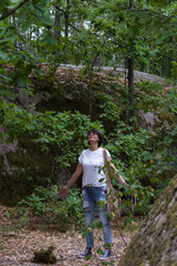 woman in a wild forest among huge boulders spread her arms and threw her head back