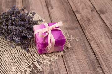 Obraz na płótnie Canvas Bars of natural handmade soap with lavender extract and lavender flowers on natural wooden background with copyspace. Home spa treatments. Natural cosmetics concept