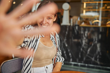 Smiling female is lookinging the camera by her hand in cafe