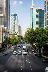 Perspectiva de calle en gran ciudad con tráfico y árboles y rascacielos al fondo generando un punto de fuga.