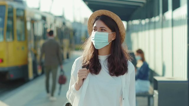 Portrait beautiful woman with hat in medical mask look around standing at bus stop train station positive mood tourists spending time resting summer vacations pandemic quarantine slow motion